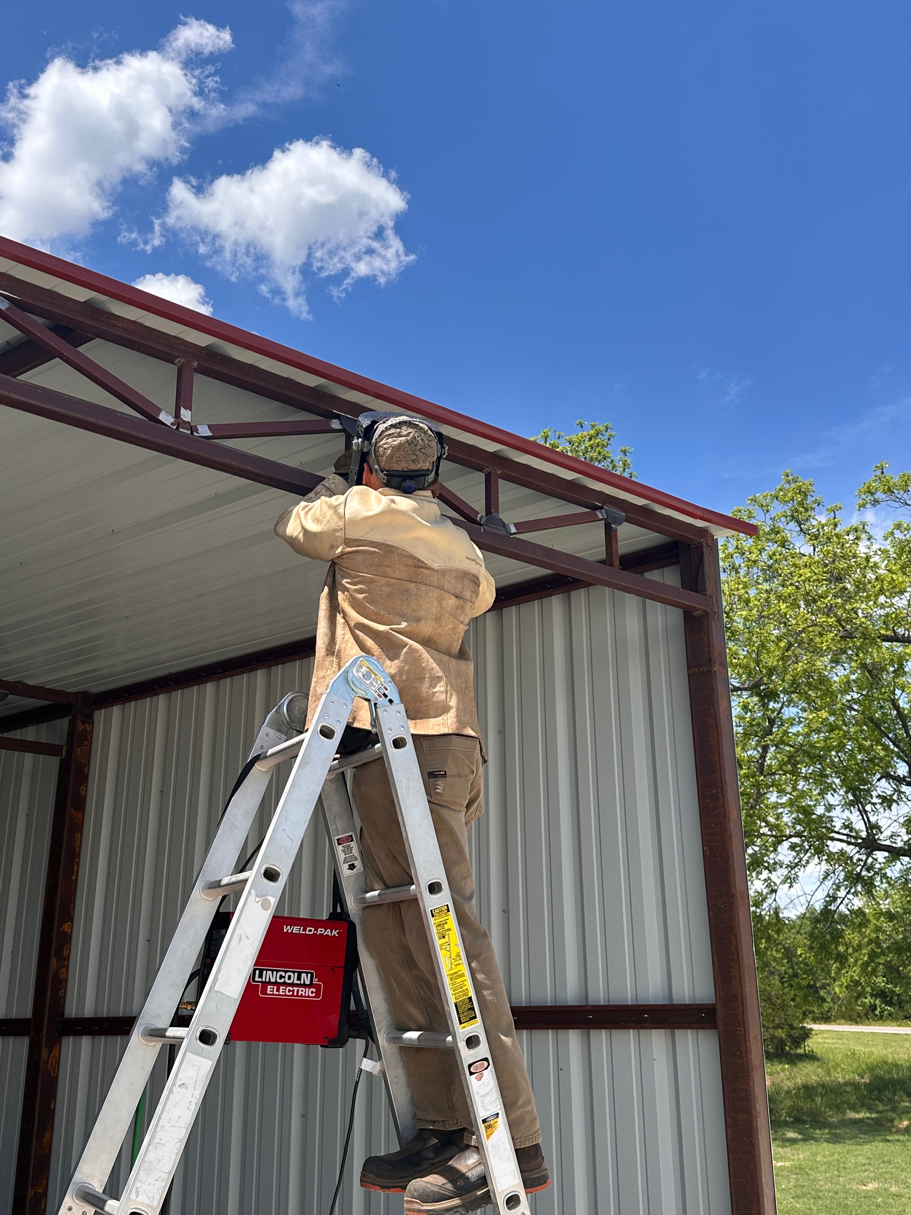 On-site field welding on red iron steel frame for structural repair and fabrication support.